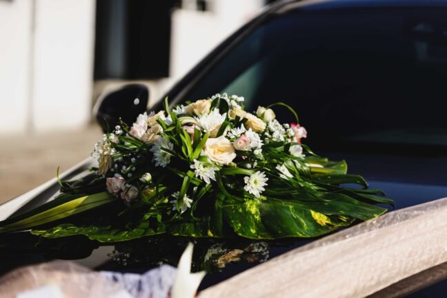 Beautiful floral arrangement on a wedding car, featuring white and pink flowers with greenery, perfect for a wedding day.